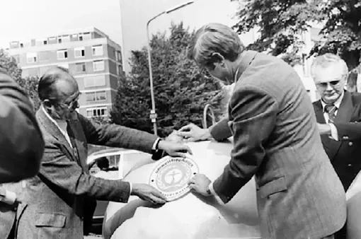 A black and white photograph shows president Freiherr von Lersner affixing the “Blue Angel” logo to a glass container