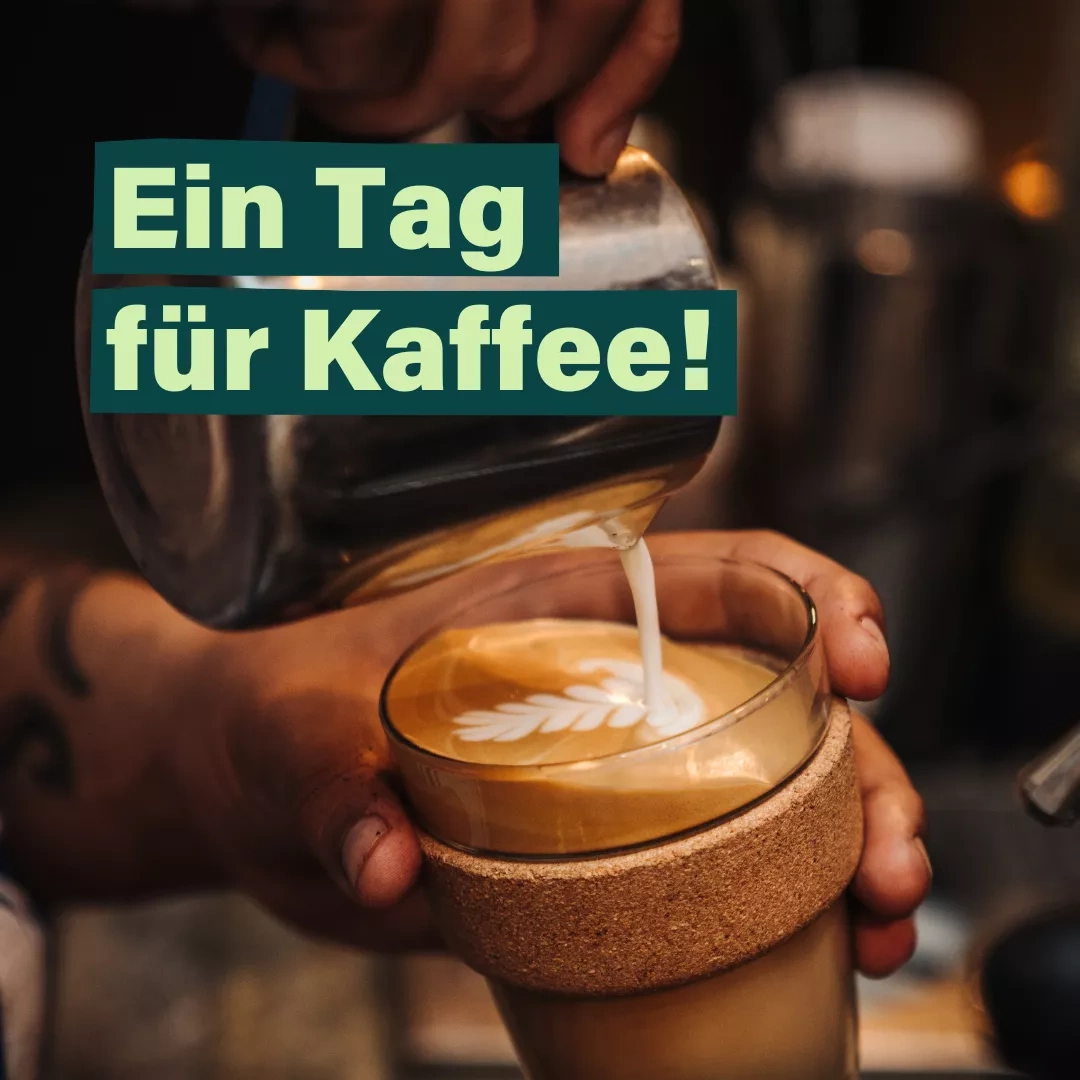 Eine Hand hält einen gläsernen Becher mit Korkring und gießt auf den Kaffee im Becher frischen Milchschaum - Daneben steht in Grüner Schrift Ein Tag für Kaffee