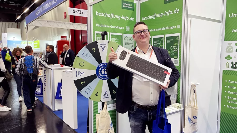 A man holds up a package with a keyboard in front of the Federal Environment Agency's exhibition stand 