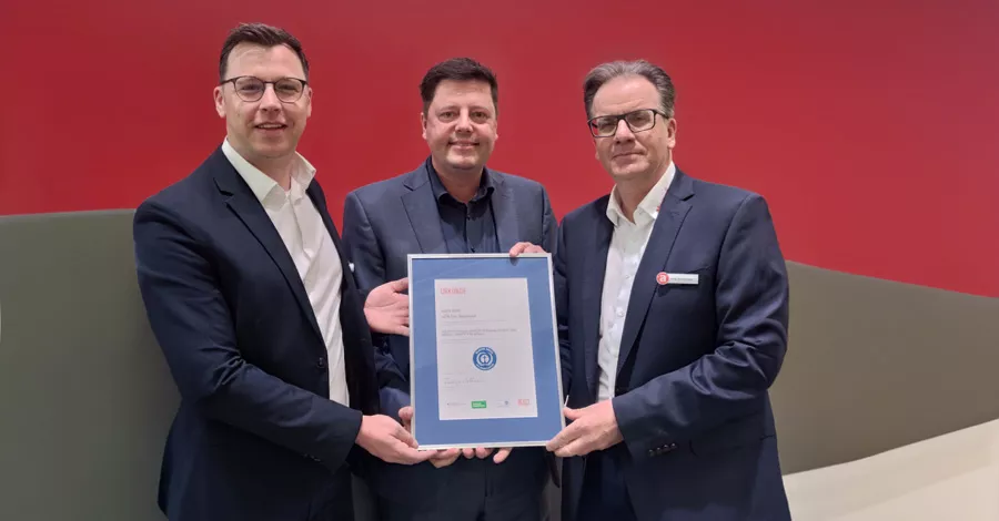 Three men in suits holding a framed certificate