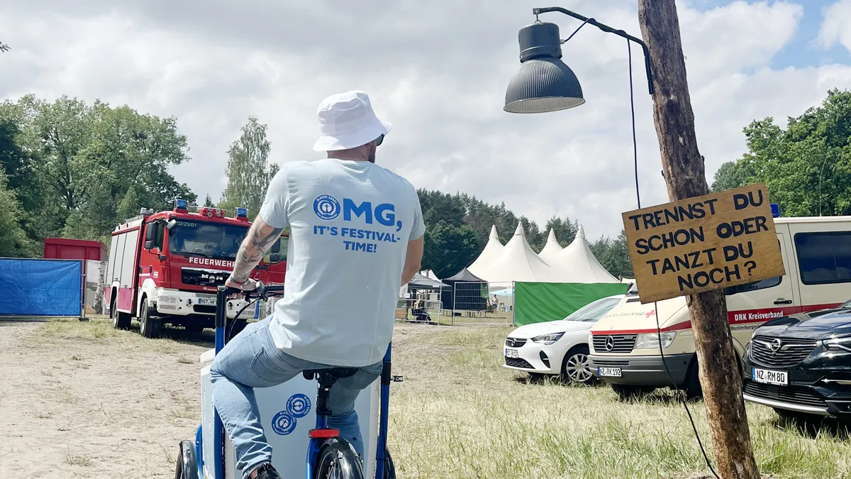 Man on cargo bike, next to a sign with the inscription “Are you still dancing or are you already separating?