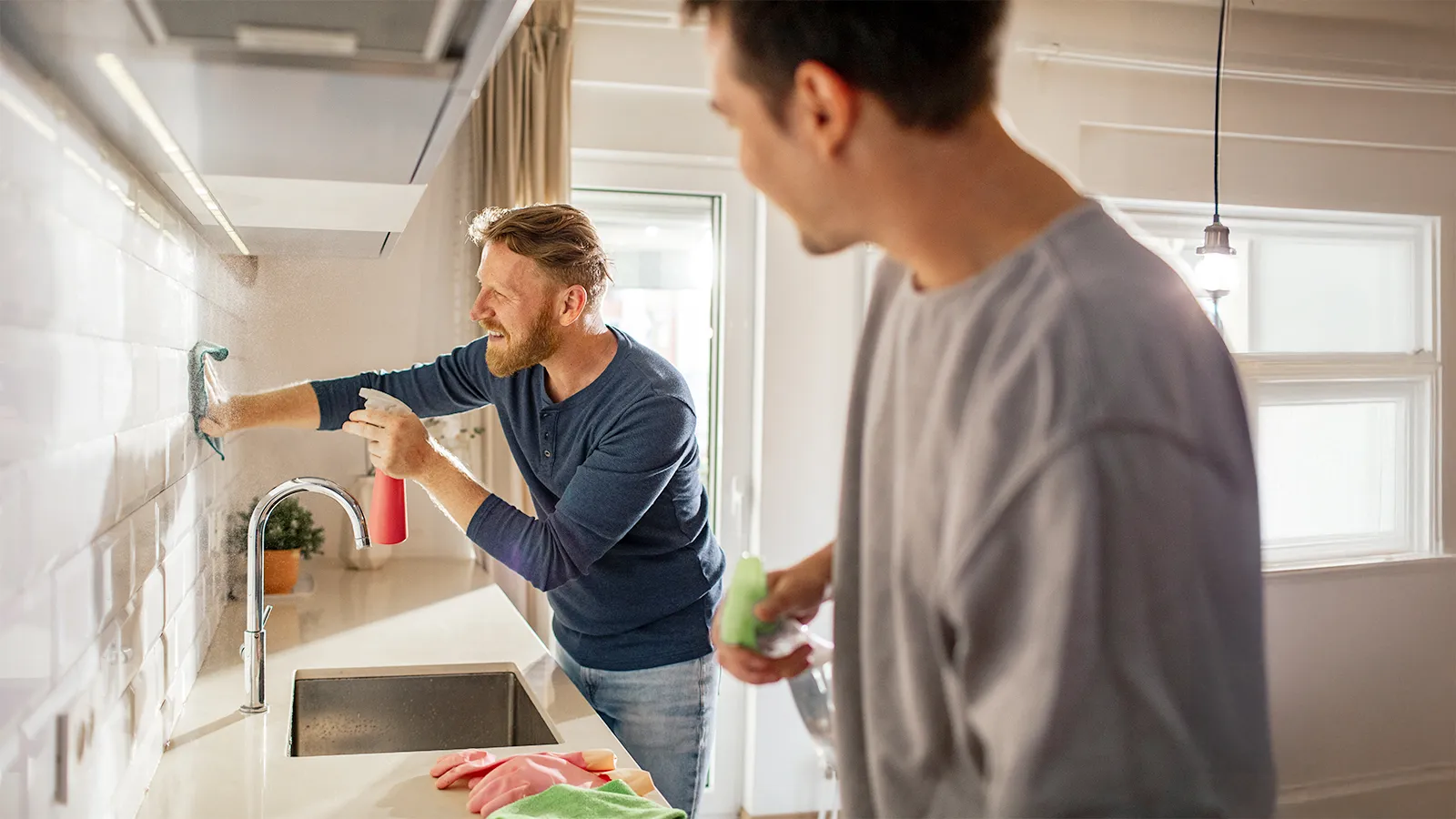 Two men cleaning a kitchen unit