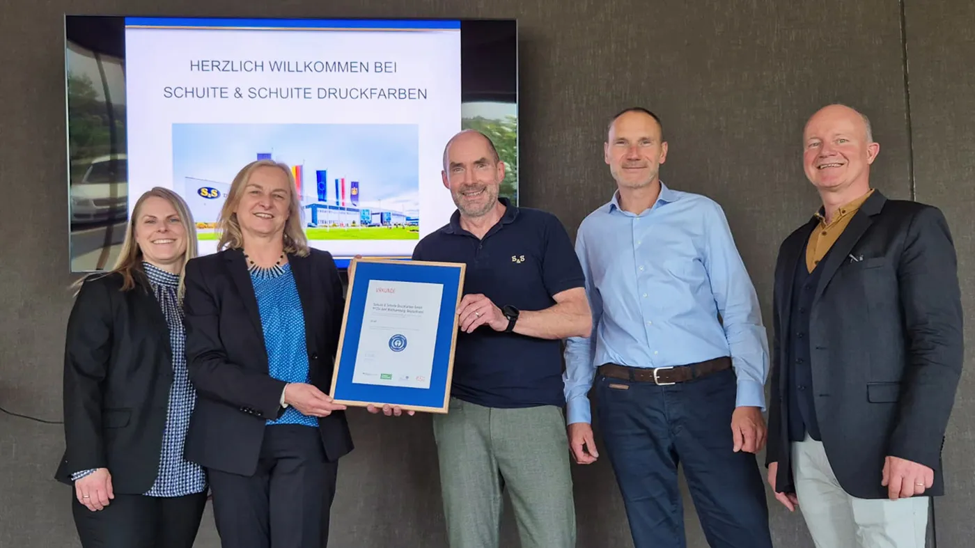 Two smiling women and three men. Two are holding up the certificate.